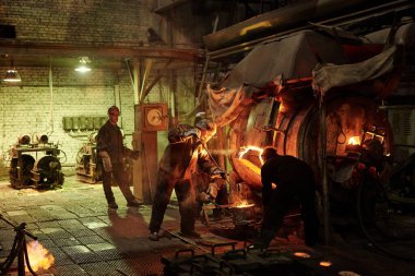 Çelik fabrikasında demir eriten işçiler.