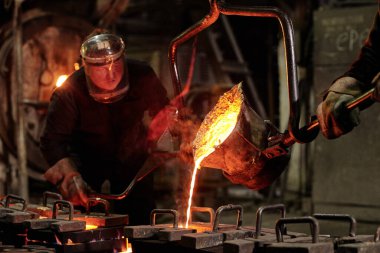 Kask takan işçiler metal fabrikasında demir eritiyorlar.