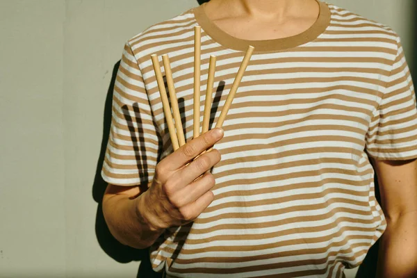 Mão Jovem Mulher Shirt Listrada Segurando Paus Enquanto Contra Parede — Fotografia de Stock