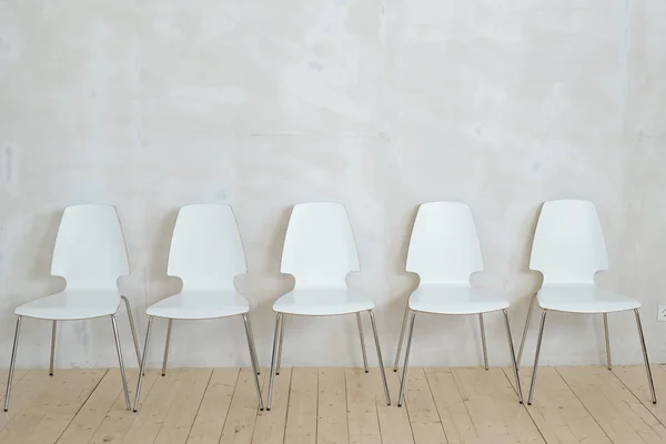 Row White Plastic Chairs Metal Legs Placed Parquet Gray Wall — Stock Photo, Image