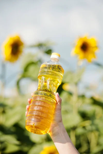 带新鲜葵花籽油的塑料瓶 与乡村环境中的绿色植物 黄色大花和黑色种子相抗衡 — 图库照片