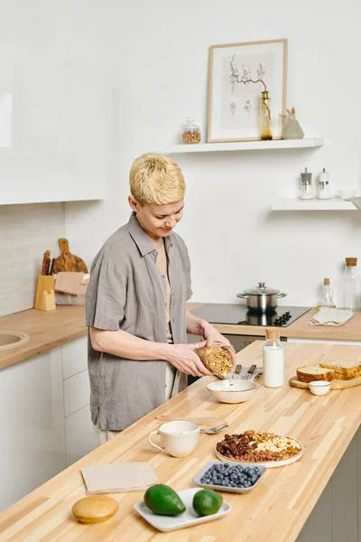 Молодая Женщина Делает Мюсли Завтрак Кухонным Столом — стоковое фото