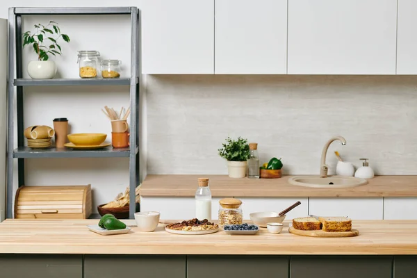 キッチン用品を完備した棚付きの大きなモダンなキッチンと食事付きの木製テーブル — ストック写真
