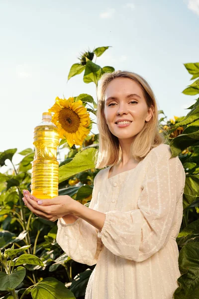 Hermosa Joven Rubia Sosteniendo Botella Aceite Girasol Mientras Está Pie —  Fotos de Stock