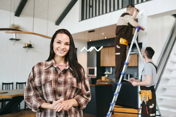 Ung Glad Brunett Kvinna Står Mot Två Reparatörer Som Arbetar — Stockfoto