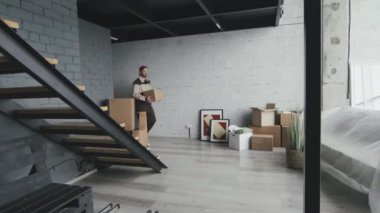 Karton kutuları boş eve ya da daireye taşıyan üniformalı erkek nakliyecilerin yavaş yavaş takibi