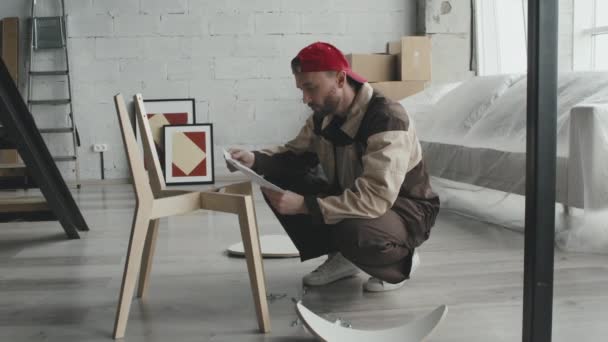 新型房屋或公寓中身着制服 头戴组装椅的杂工的慢镜头 — 图库视频影像