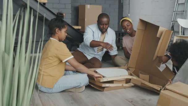 Lento Plano Medio Familia Afroamericana Sentada Suelo Nueva Casa Abriendo — Vídeos de Stock