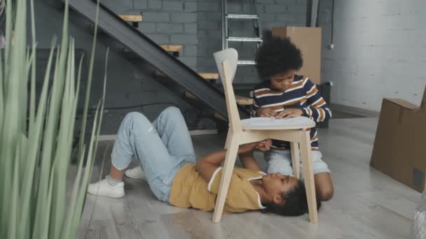 Slowmo Pan Afroamerykanki Chlopca Montujacego Drewniane Krzeslo Razem Mieszkaniu Poddaszu — Wideo stockowe