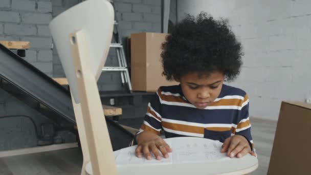 Slowmo Plano Medio Niño Afroamericano Pequeño Instrucciones Lectura Para Montaje — Vídeos de Stock