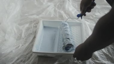 Tanınmayan Afro-Amerikalı adamın yavaş yavaş yaklaşarak evi yenilerken boya rulosuyla boya toplaması.