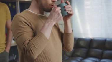 Neşeli eşcinsel bir adamın konuşmasının ve erkek ortağına sarılmasının ve evlerinde kahve içmesinin yavaşlığını takip ediyor.