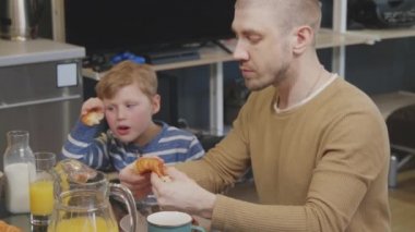 Eşcinsellerin ve şirin çocuğun birlikte mutfak masasında oturup kahvaltı etmelerinin yavaş çekimleri.