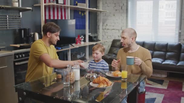 一对同性恋夫妇和他们的小儿子在舒适的公寓里围坐在桌旁享用早餐的慢镜头 — 图库视频影像