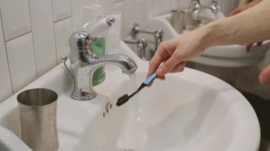 Diş fırçalarken diş fırçalarını ıslatan tanınmayan adamların el kamerası görüntüleri.