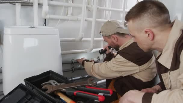 Handheld Slow Tracking Shot Two Male Plumbers Uniform Inspecting Fixing — Vídeos de Stock