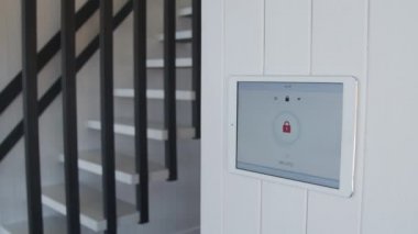 Duvara asılmış tablet akıllı ev güvenlik sistemini kapatırken genç bir kadının eve girişinin yavaş çekimleri
