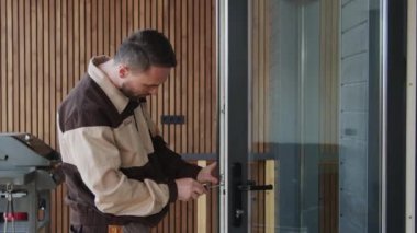 Tornavida kullanan ve kapı kilidini tamir eden üniformalı bir işçinin yavaş çekimleri.