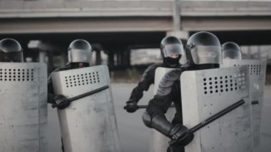 Protestocuları sindirirken kalkanlarını coplarla döven tanınmayan çevik kuvvet polislerinin yavaş çekimleri.
