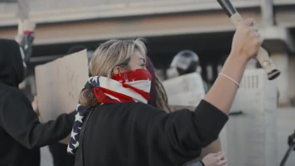 拿着标牌和棒球棒的蒙面年轻人在外面抗议 防暴警察拿着盾牌挡住街道的慢镜头 — 图库视频影像