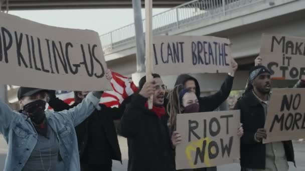 何かに抗議しながら歩くと叫んで米国のフラグと標識を持つ多様な若者のグループのスローモーション追跡を開催 — ストック動画
