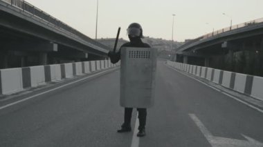 Tanımlanamayan çevik kuvvet polisinin elinde kalkan ve copla otoyolda durduğu yavaş çekim.