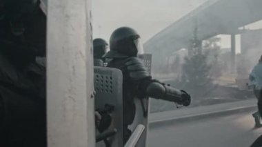 Kalkanları ve copları olan çevik kuvvet polislerinin yavaş çekimleri protestocuların peşinden koşuyor.