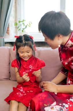 Anne kırmızı kartpostalla kızının yanında oturuyor.