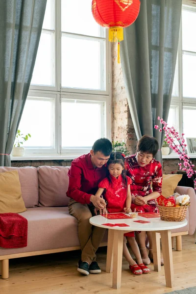 Parents and daughter preparing postcards for Chinese new year — Stock Photo, Image