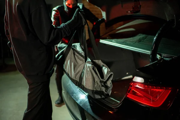 Δύο χάκερ να βάζουν σακούλες στο πίσω μέρος του αυτοκινήτου. — Φωτογραφία Αρχείου