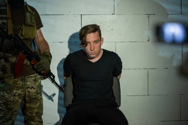 Sullen criminoso sentado por parede durante a confissão — Fotografia de Stock