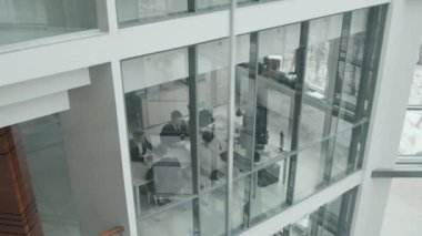 Büyük modern ofisin cam konferans odasında müzakere masasında oturan iş adamlarının yavaşlaması.