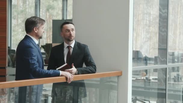 양복을 변호사나 사업가가 현대식 사무실 층에서 서성거리는 모습을 미디엄 — 비디오