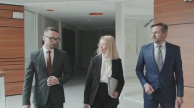 Formalite icabı başarılı avukatlardan oluşan orta karar bir ekip modern ofiste yürürken dava hakkında konuşuyor.