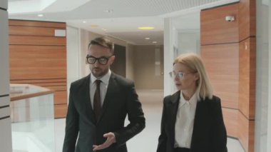 Modern ofiste yürürken resmi kıyafet giymiş iki avukat veya iş ortağının orta boy görüntüsü.