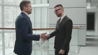 Orta ölçekli başarılı, olgun iş adamı ve avukatı modern ofiste el sıkışıyor.