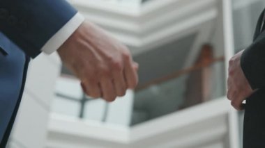 Takım elbiseli iki tanınmayan iş adamının yavaş yavaş el sıkışması.