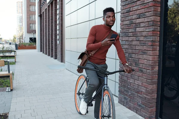 Jonge zakenman met smartphone tijdens het fietsen — Stockfoto