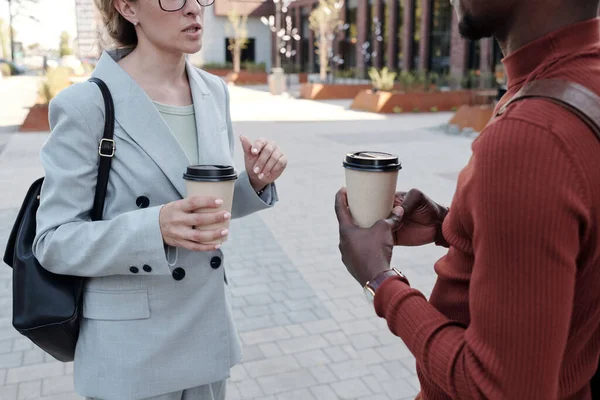 Mužské a ženské spolupracovnice s nápoji interagující na ulici — Stock fotografie