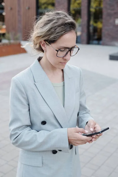 Üzletasszony szemüvegben és öltönyben okostelefonnal — Stock Fotó