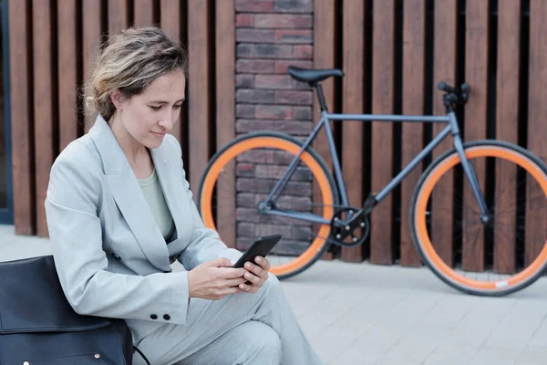 Joven mujer de negocios mensajes de texto en el teléfono inteligente al aire libre — Foto de Stock