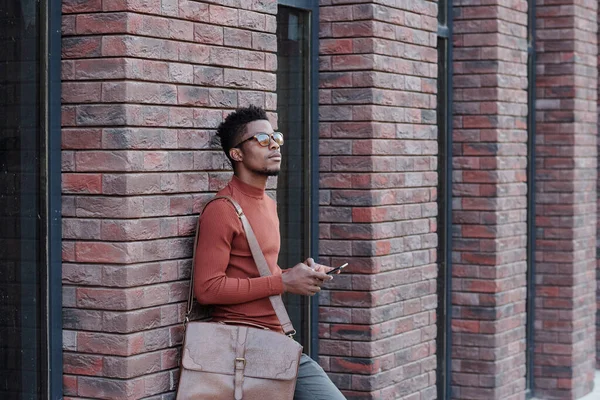 Entspannter junger Geschäftsmann steht an Mauer moderner Architektur — Stockfoto