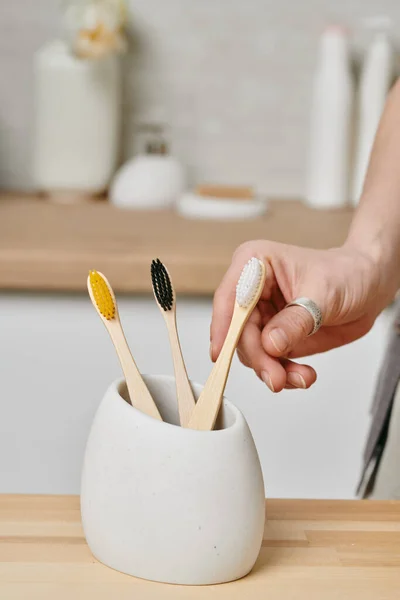 Hand van vrouwelijke het nemen van tandenborstel uit witte kom — Stockfoto