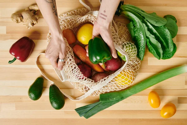 Manos de mujer joven sacando verduras frescas de la bolsa — Foto de Stock