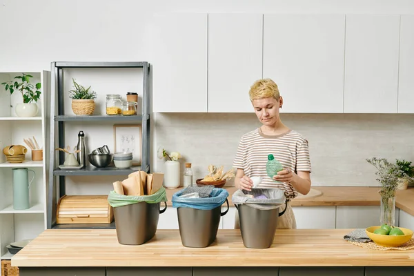 Mujer rubia joven clasificando la basura en tres contenedores — Foto de Stock