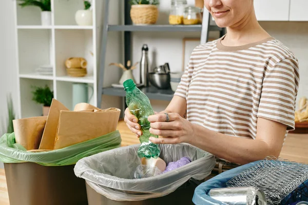 Genç bir kadın çöp kutusunda plastik şişe kırıyor. — Stok fotoğraf