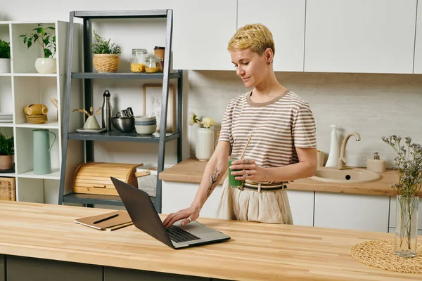 Young businesswoman with vegetable smoothie working in the net — Stock Photo, Image