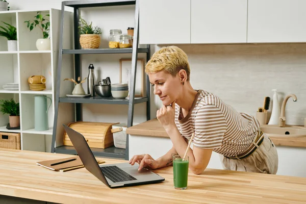 Mujer de negocios contemporánea con ordenador portátil doblado sobre la mesa de la cocina — Foto de Stock