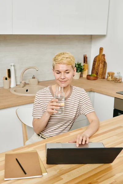 Businesswoman with glass of pure water using laptop — Stock Photo, Image