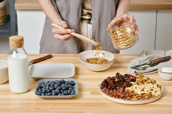 Mani di femmina che mettono il muesli nella ciotola — Foto Stock